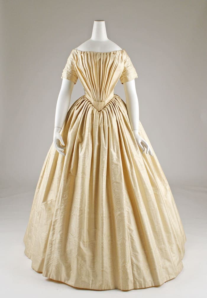 A cream silk wedding dress from about 1844 with an off-the-shoulder bodice and full skirt